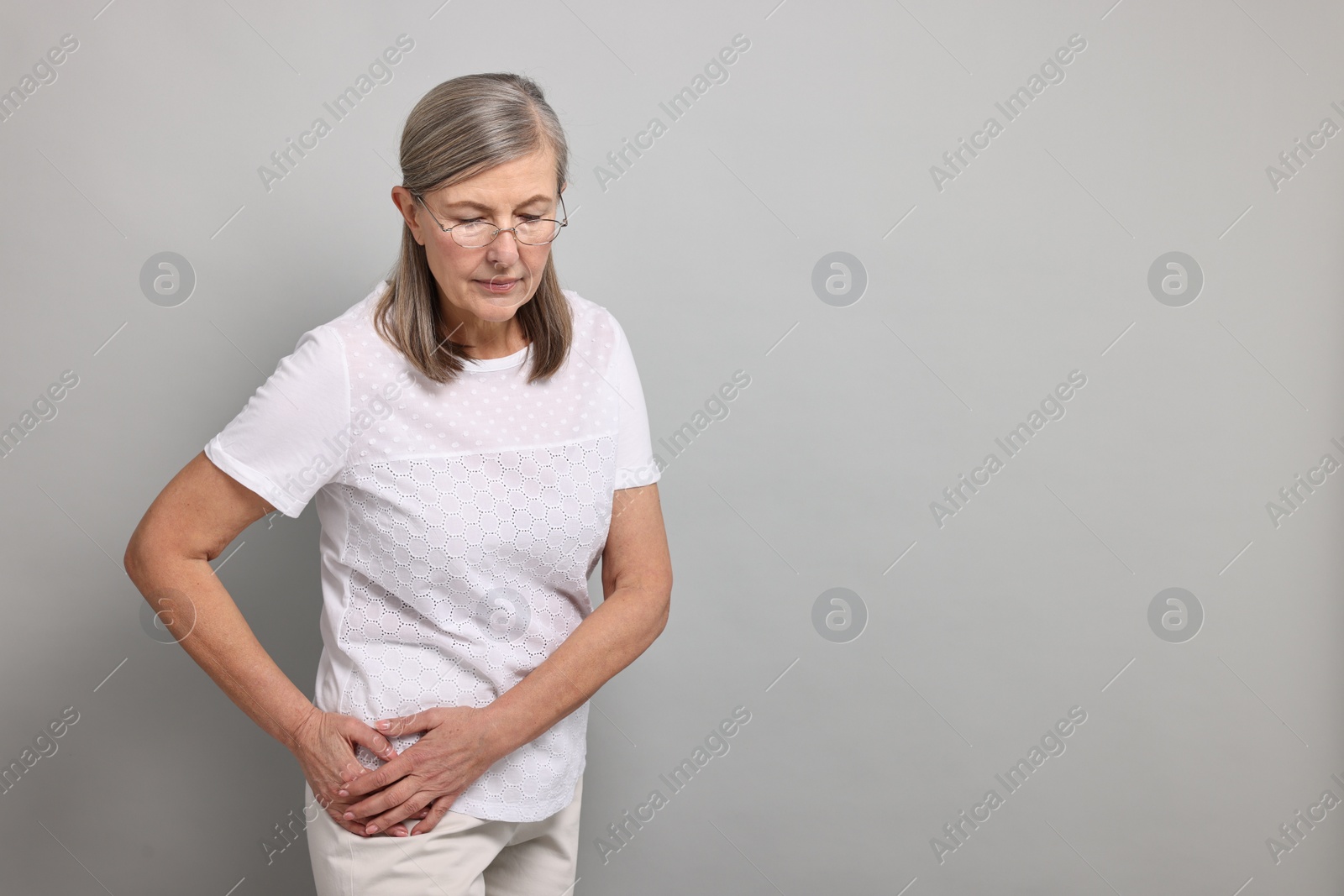 Photo of Arthritis symptoms. Woman suffering from hip joint pain on gray background, space for text