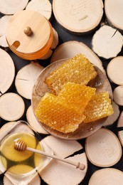 Photo of Natural honeycombs with honey and wooden dipper on textured table, flat lay