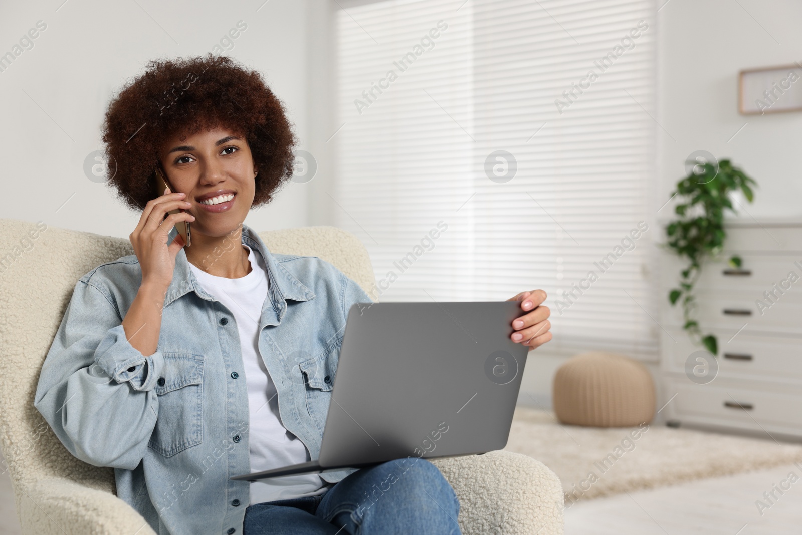 Photo of Young woman using laptop and talking on smartphone in room, space for text