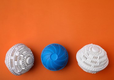 Photo of Laundry dryer balls on orange background, flat lay. Space for text