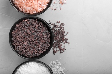 Photo of Different kinds of salt on light grey marble table, flat lay. Space for text