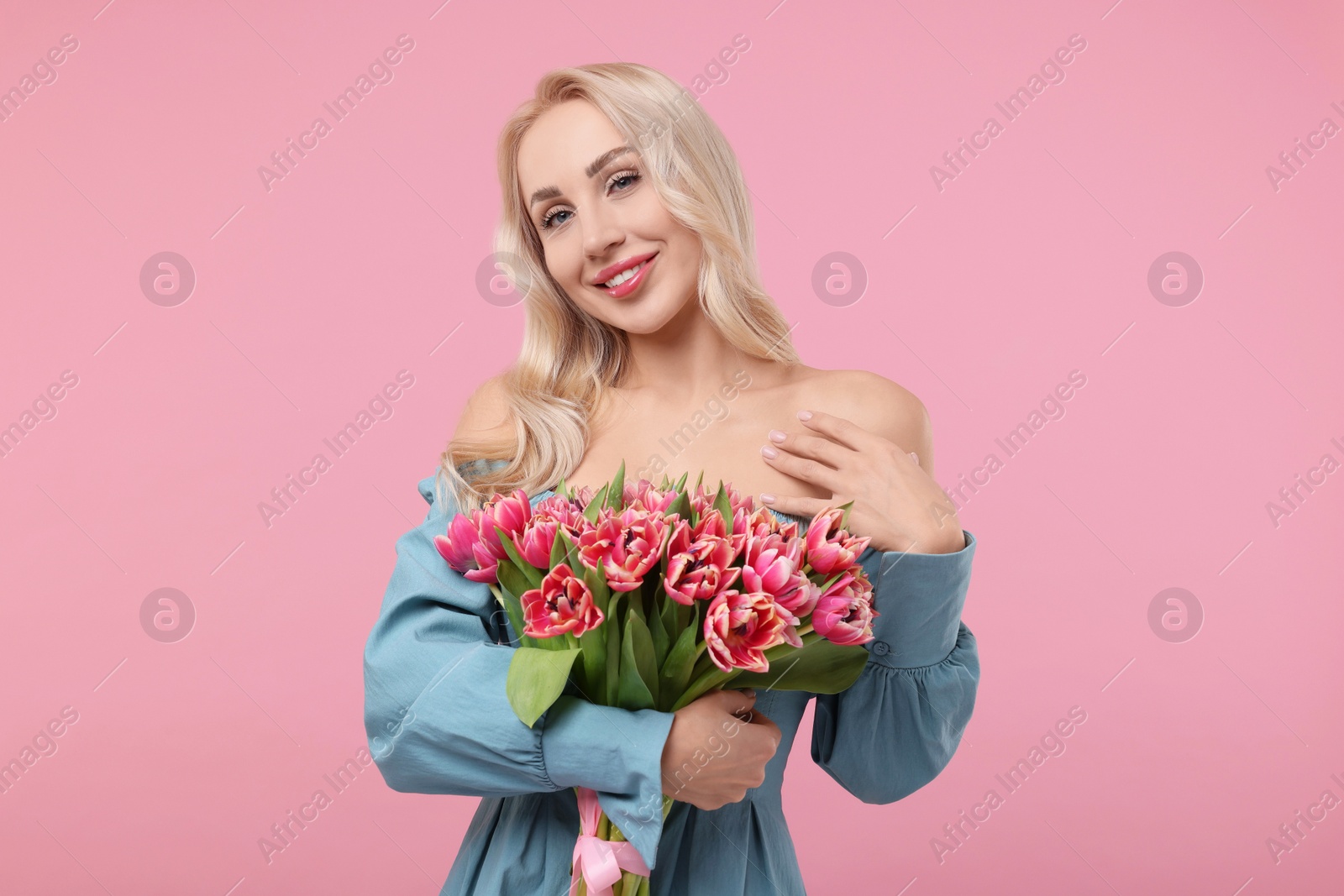 Photo of Happy young woman with beautiful bouquet on dusty pink background