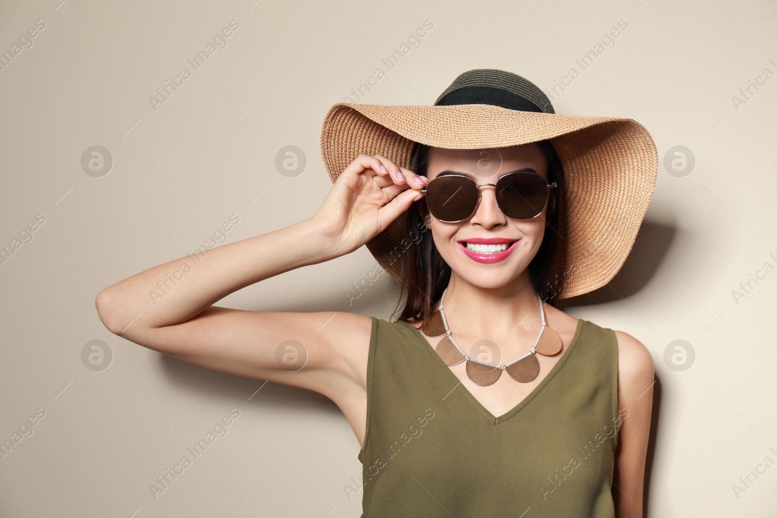 Photo of Beautiful woman in stylish sunglasses and hat on beige background