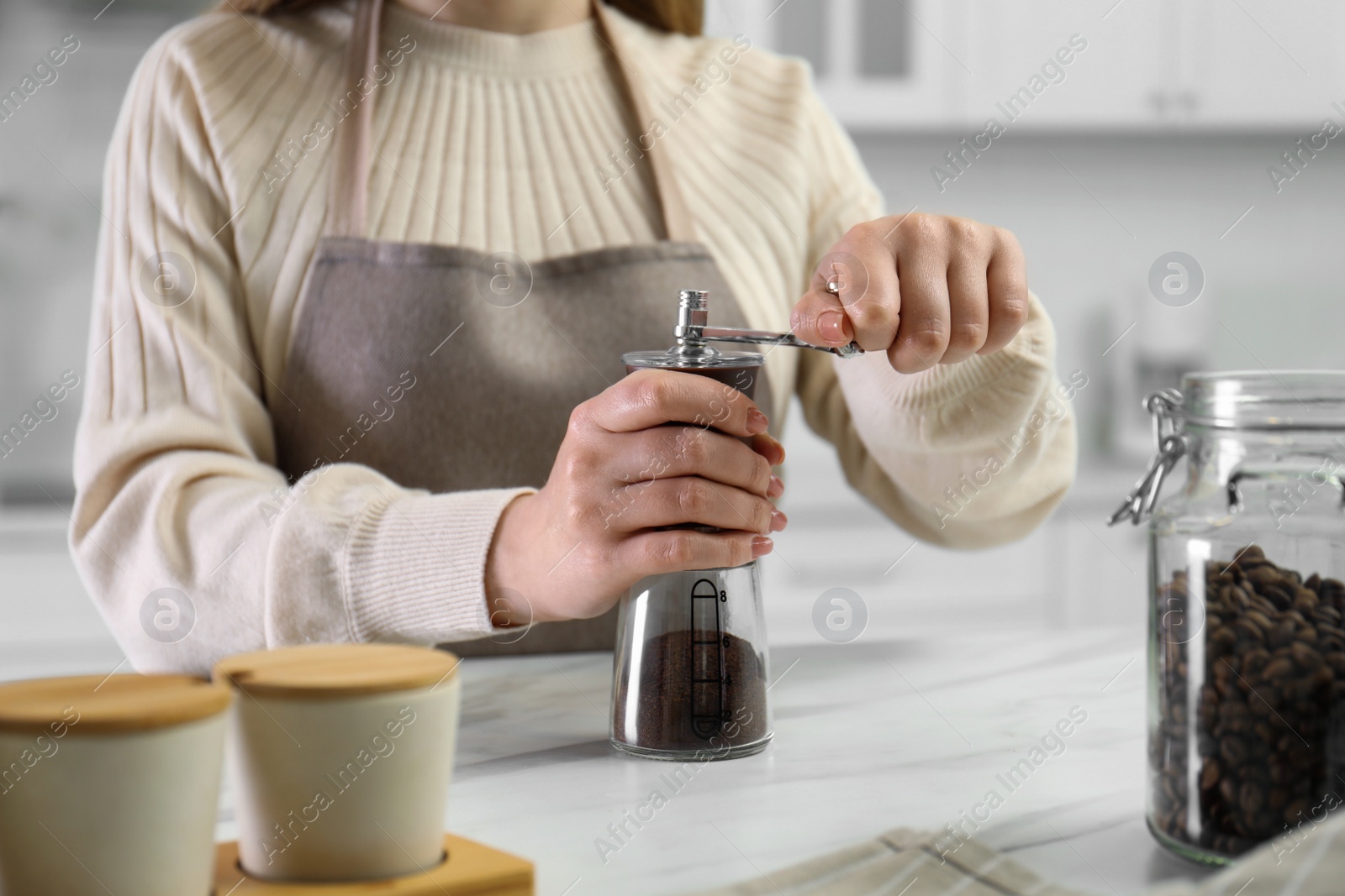 Photo of Woman using coffee grinder at table indoors, closeup