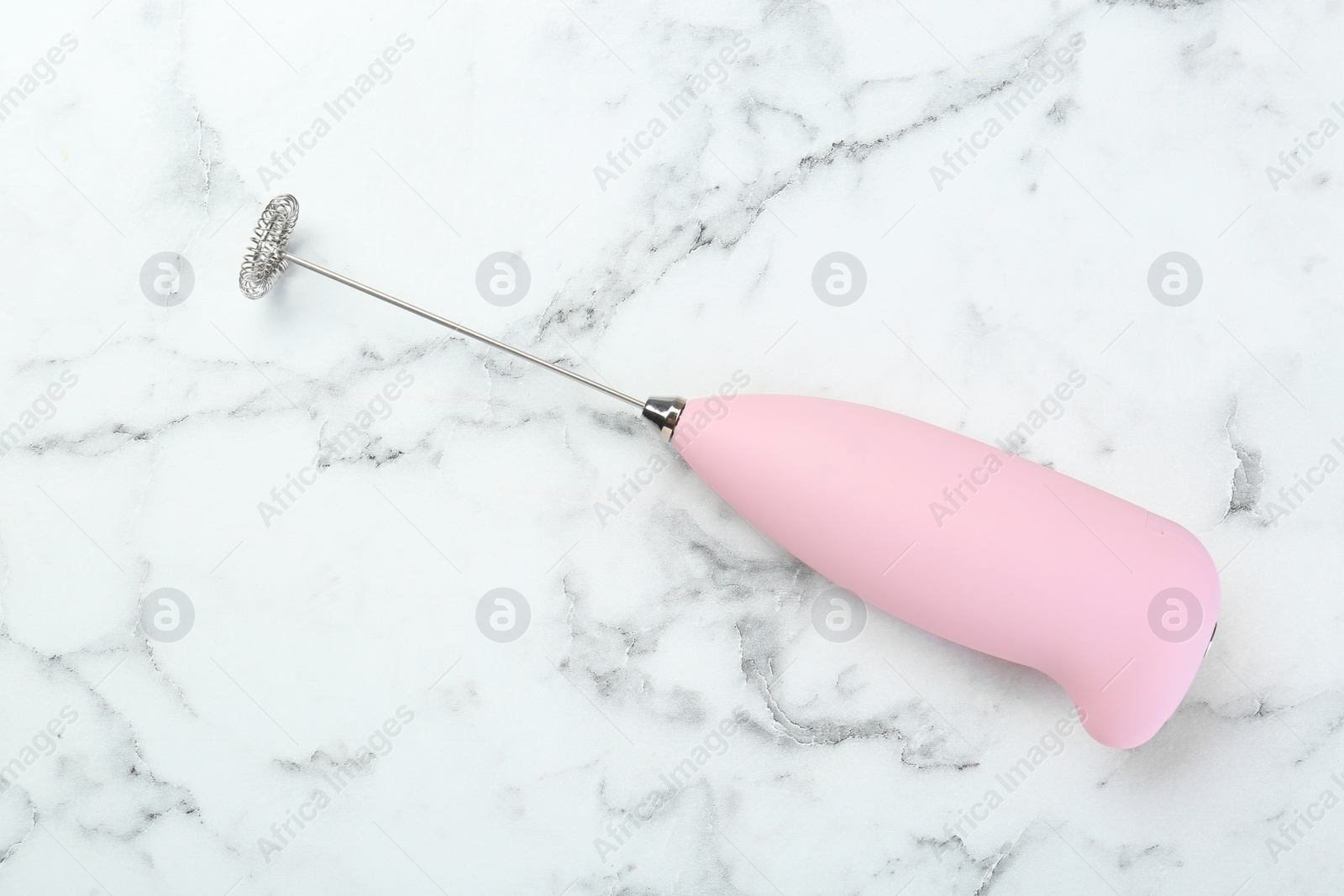 Photo of Pink milk frother wand on white marble table, top view