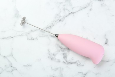 Pink milk frother wand on white marble table, top view