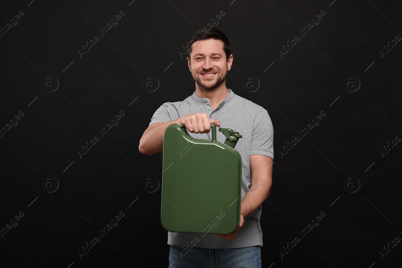 Photo of Handsome man holding khaki metal canister on black background