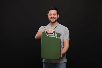 Photo of Handsome man holding khaki metal canister on black background