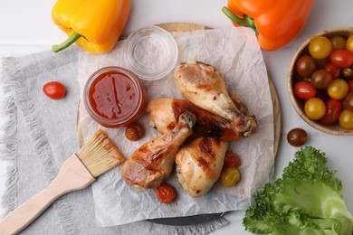 Flat lay composition with marinade and roasted chicken drumsticks on white table