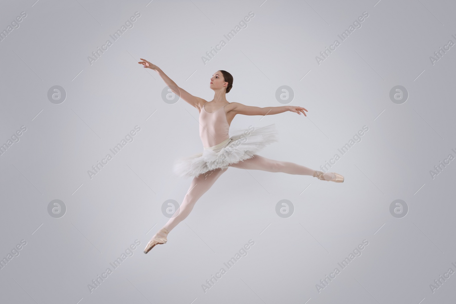 Photo of Young ballerina practicing dance moves on white background