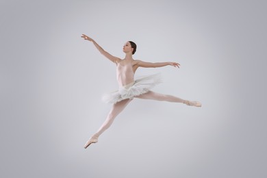 Photo of Young ballerina practicing dance moves on white background
