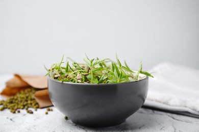Photo of Mung bean sprouts in bowl on white textured table, closeup