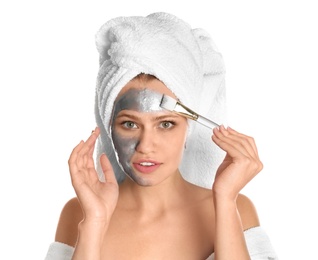 Beautiful woman applying silver mask on her face against white background
