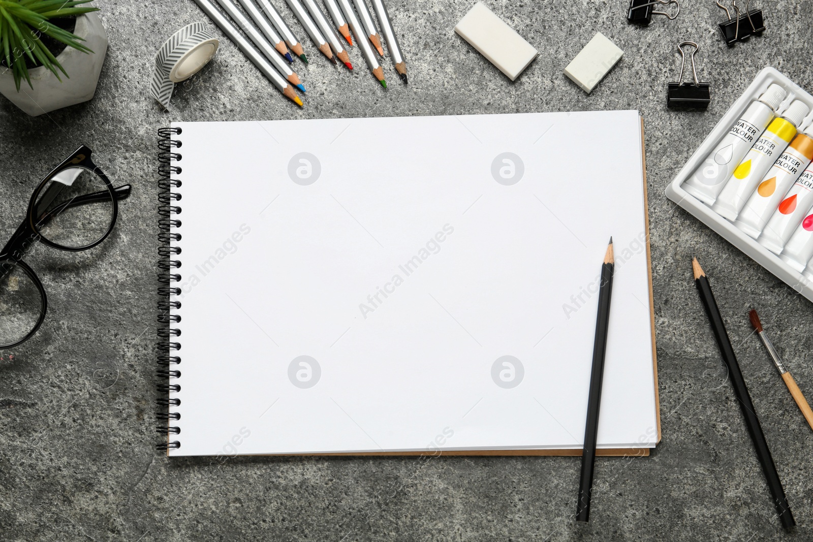 Photo of Flat lay composition with blank sketchbook on grey stone table. Space for text