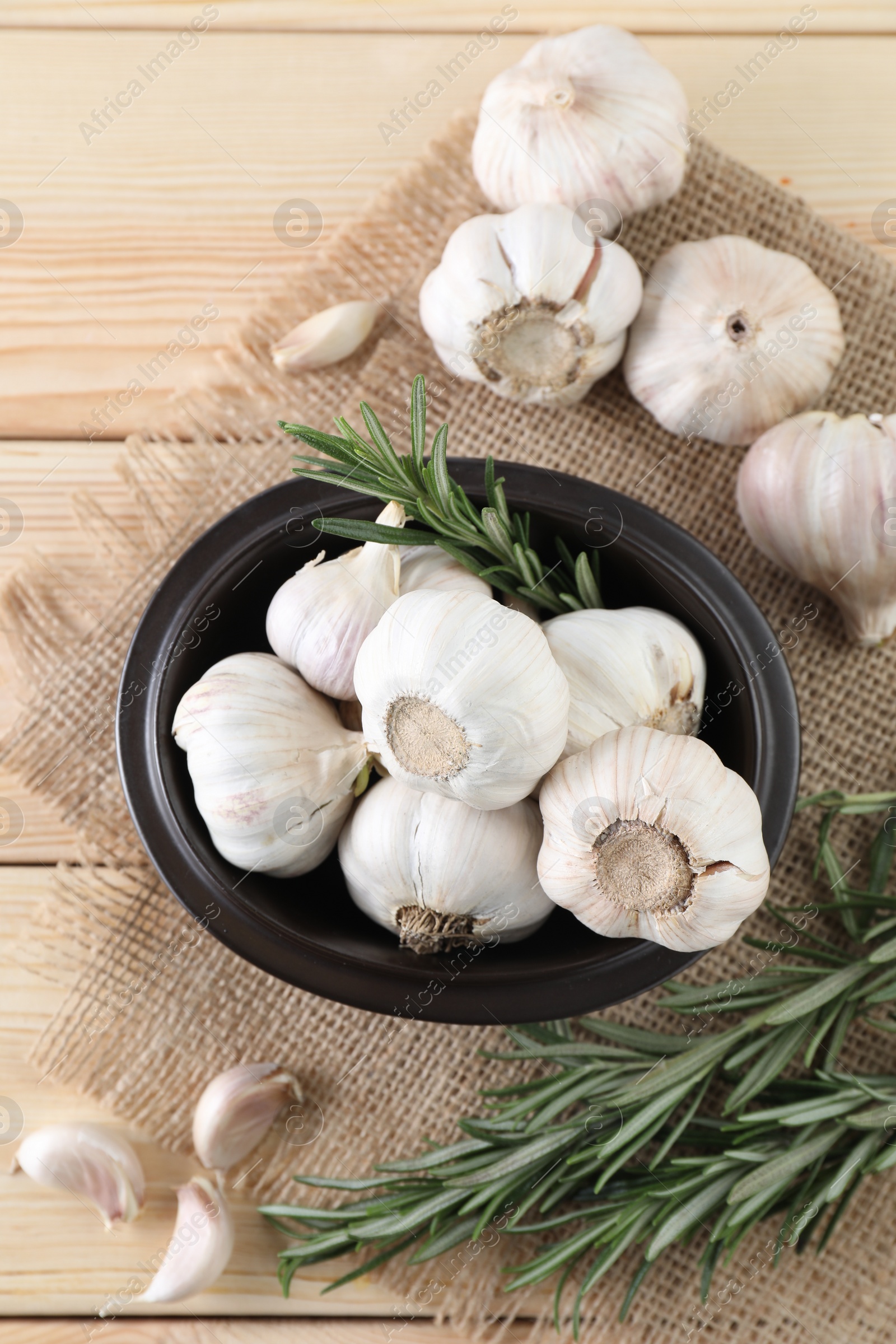 Photo of Fresh raw garlic and rosemary on wooden table, flat lay