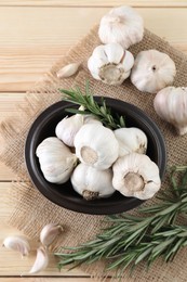 Photo of Fresh raw garlic and rosemary on wooden table, flat lay