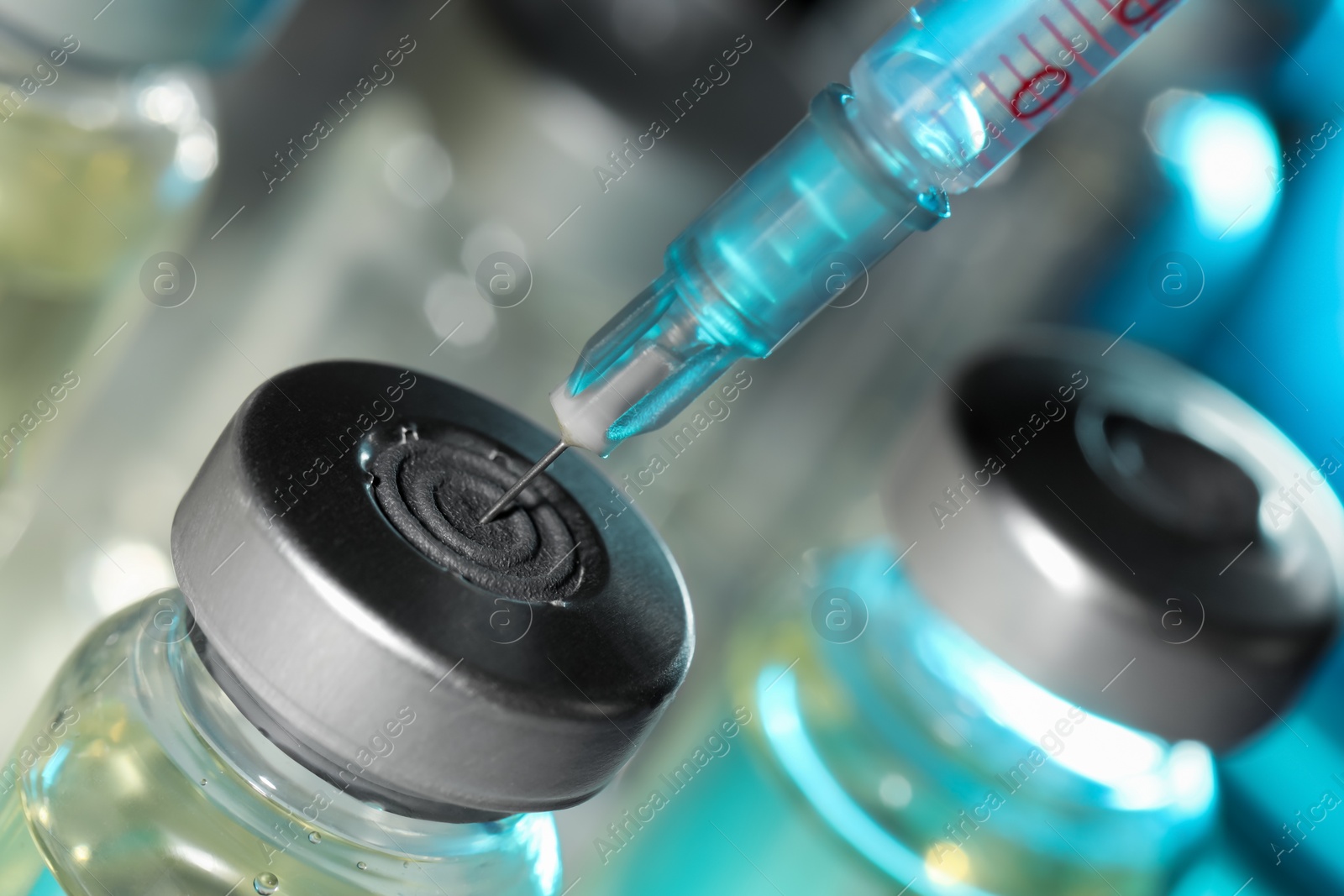 Photo of Filling syringe with medicine from vial against blurred background, closeup