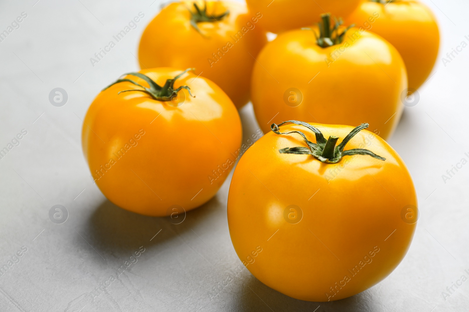 Photo of Ripe yellow tomatoes on grey table, closeup