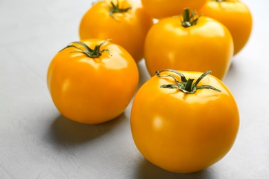 Photo of Ripe yellow tomatoes on grey table, closeup