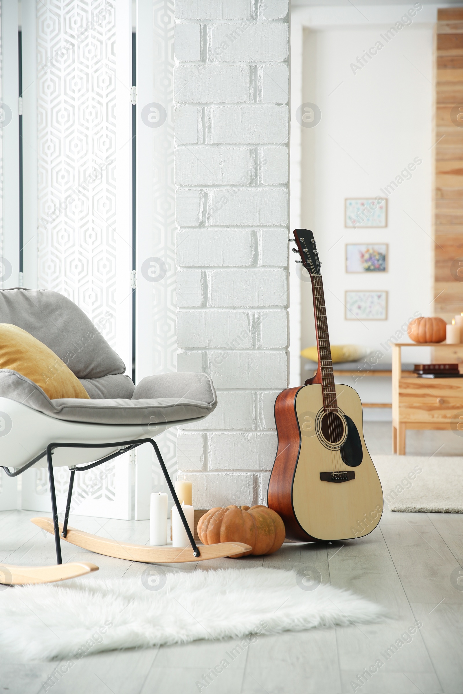 Photo of Cozy room interior with rocking chair, guitar and autumn decor