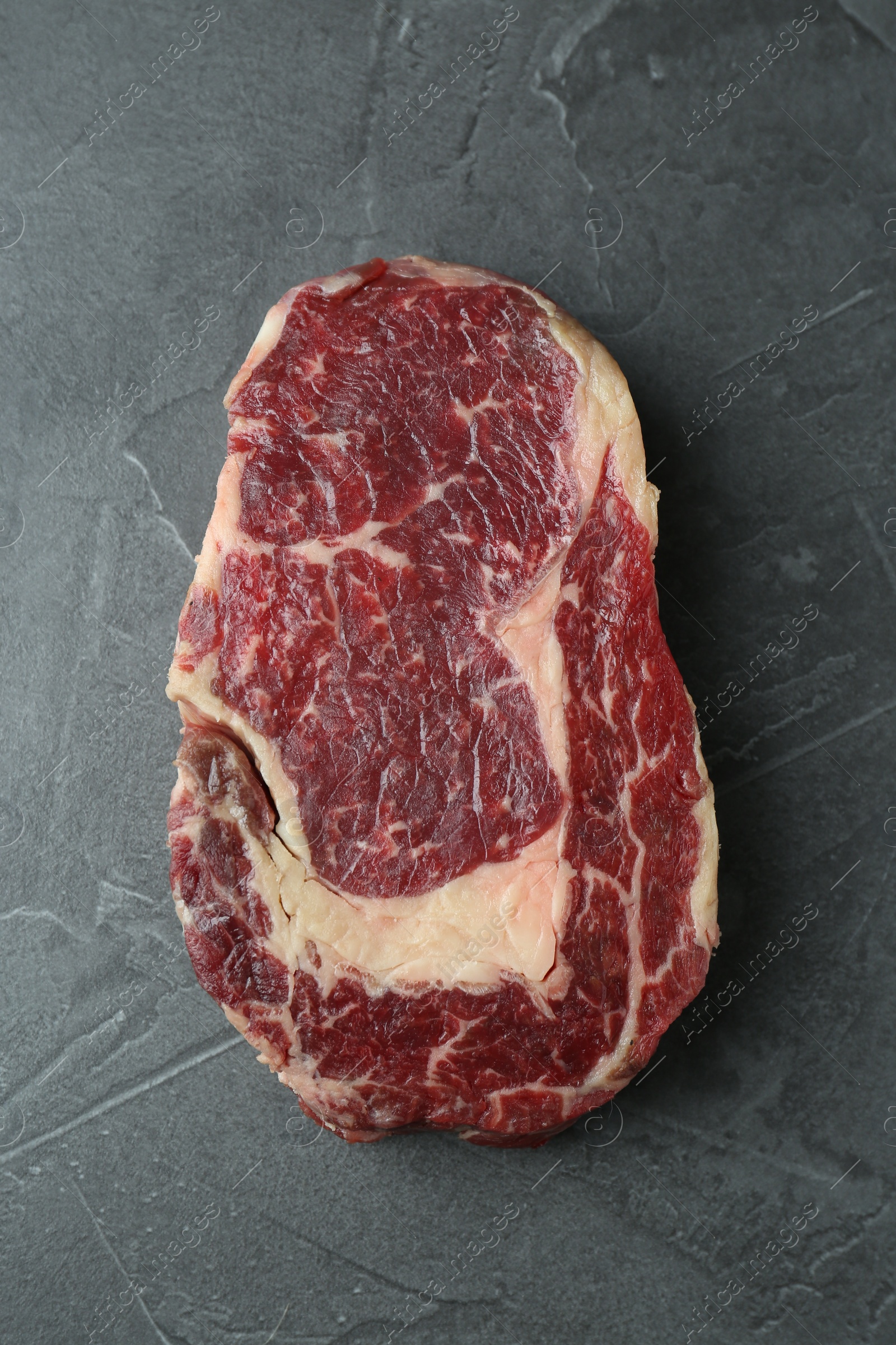 Photo of Piece of raw beef meat on grey table, top view