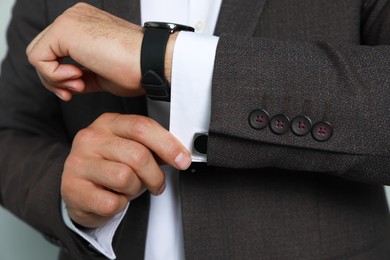 Photo of Stylish man putting on cufflink, closeup view