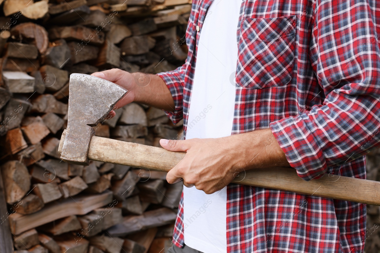 Photo of Man with sharp ax near wood pile outdoors, closeup