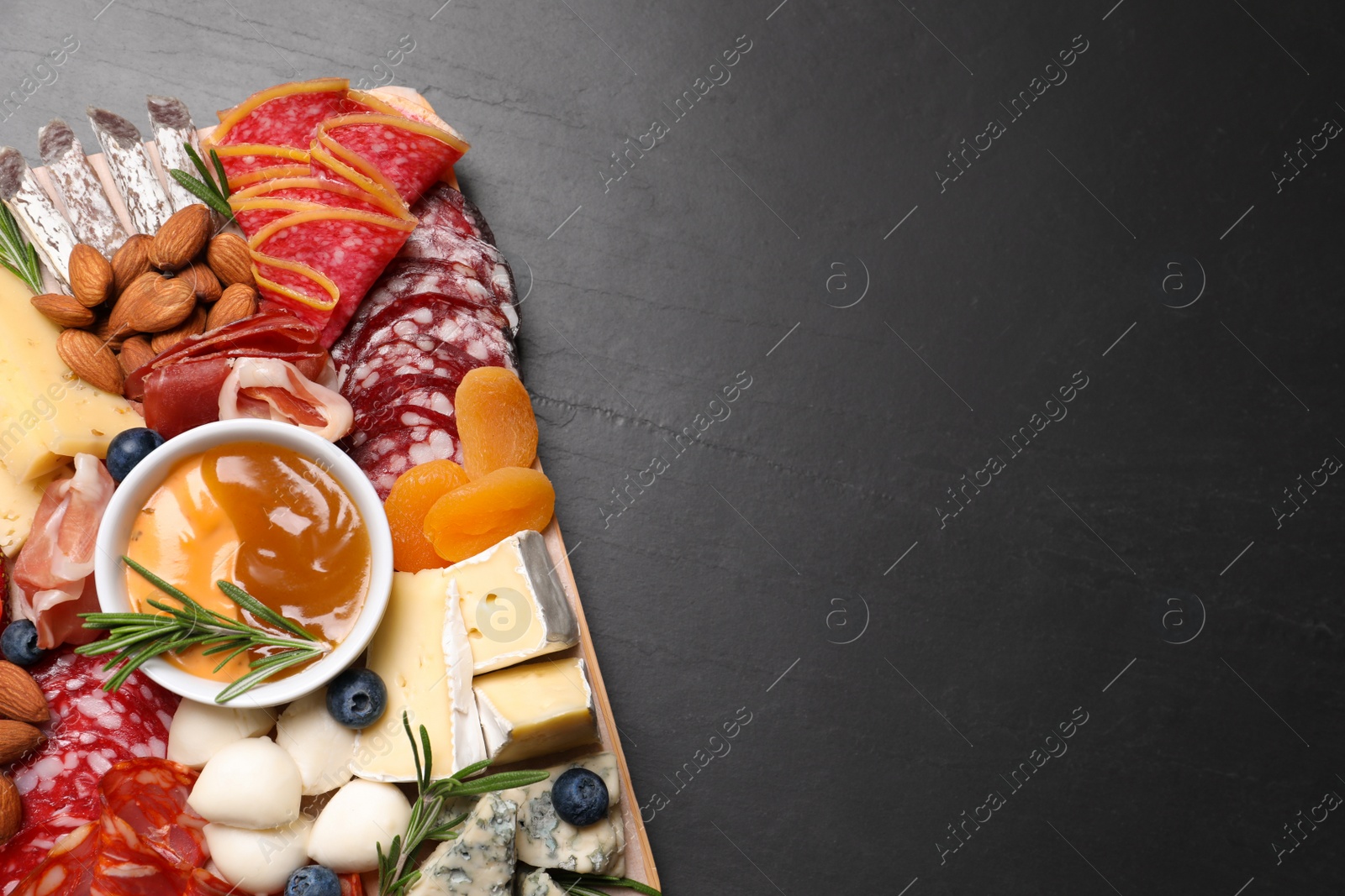 Photo of Different delicious snacks on black table, top view. Space for text