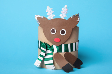 Toy deer made of toilet paper roll on light blue background
