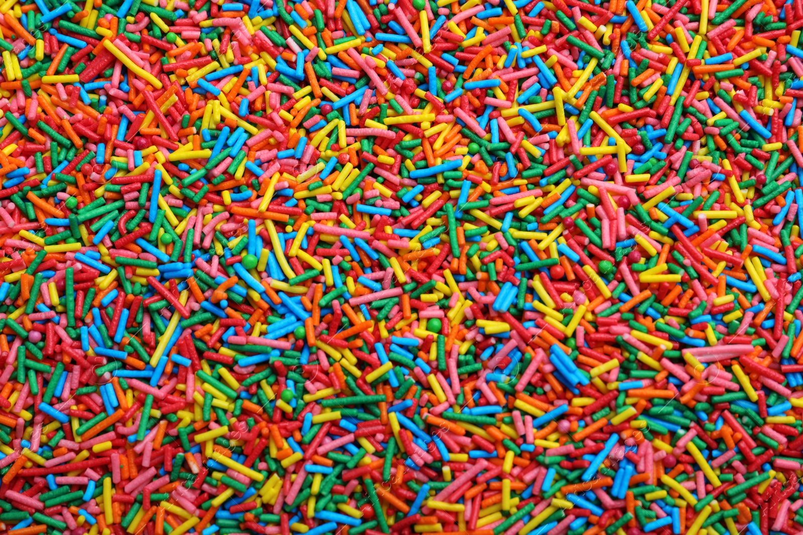 Photo of Bright colorful sprinkles as background, top view. Confectionery decor