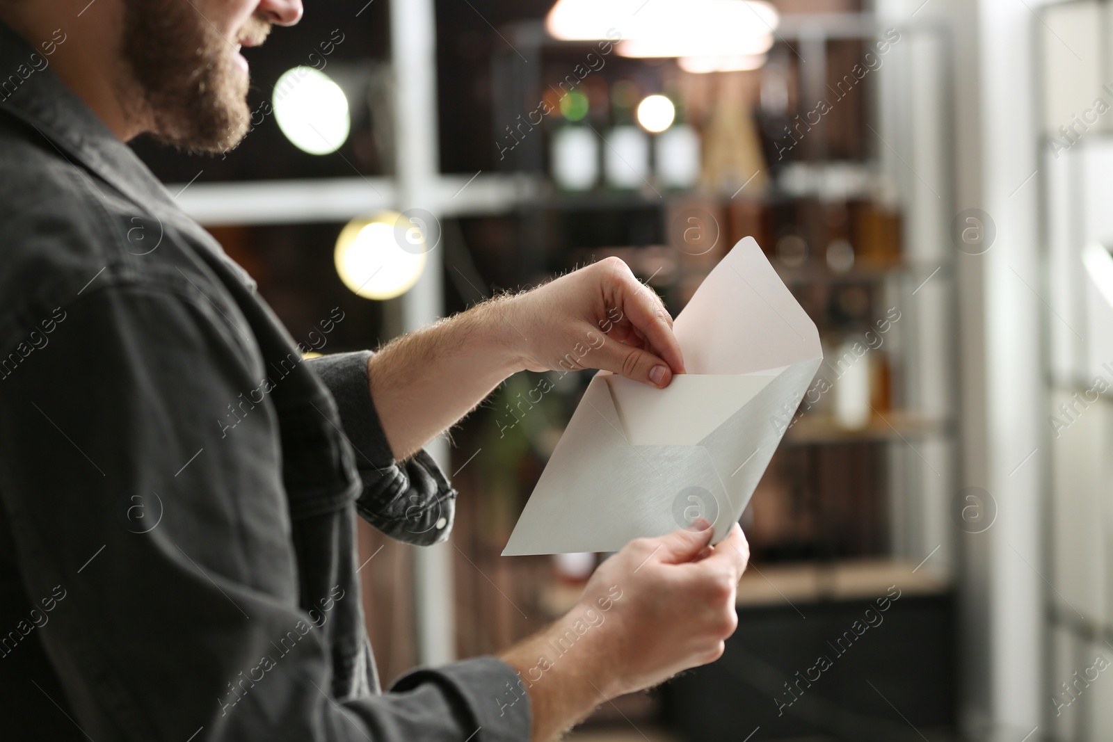 Photo of Man holding envelope with greeting card indoors, closeup