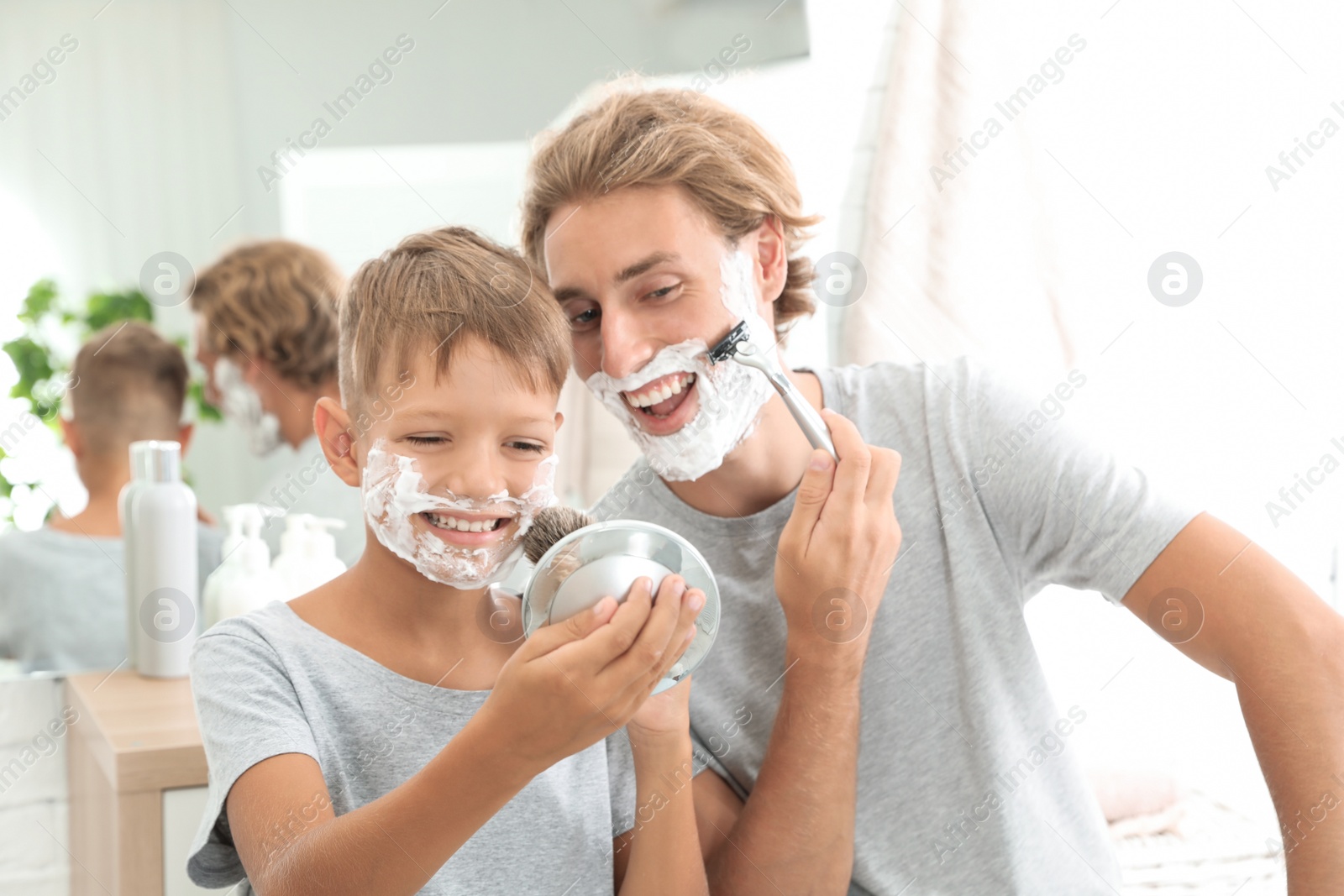 Photo of Father and son shaving together in bathroom