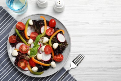 Photo of Delicious vegetable salad with mozzarella served on white wooden table, flat lay. Space for text