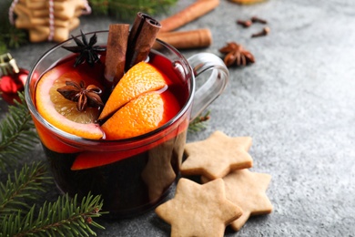 Photo of Aromatic mulled wine, cookies and Christmas decorations on grey table, closeup. Space for text