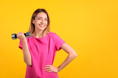 Photo of Woman with dumbbell as symbol of girl power on yellow background, space for text. 8 March concept