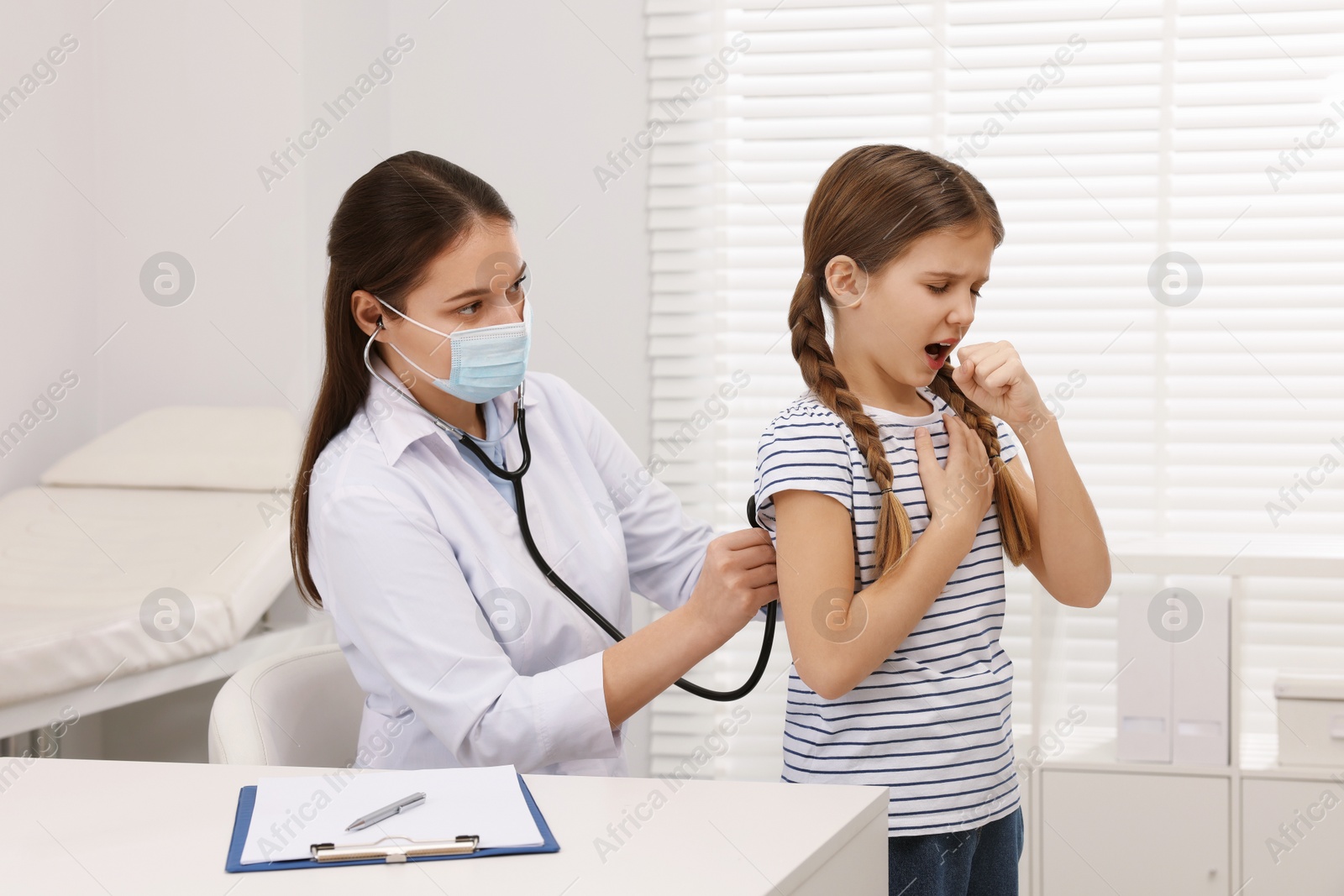 Photo of Doctor examining coughing girl in hospital. Cold symptoms