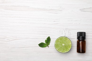 Photo of Bottle of citrus essential oil and fresh lime on white wooden table, flat lay. Space for text