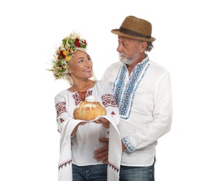 Photo of Happy mature couple in national clothes with bread and salt on white background. Ukrainian welcoming tradition