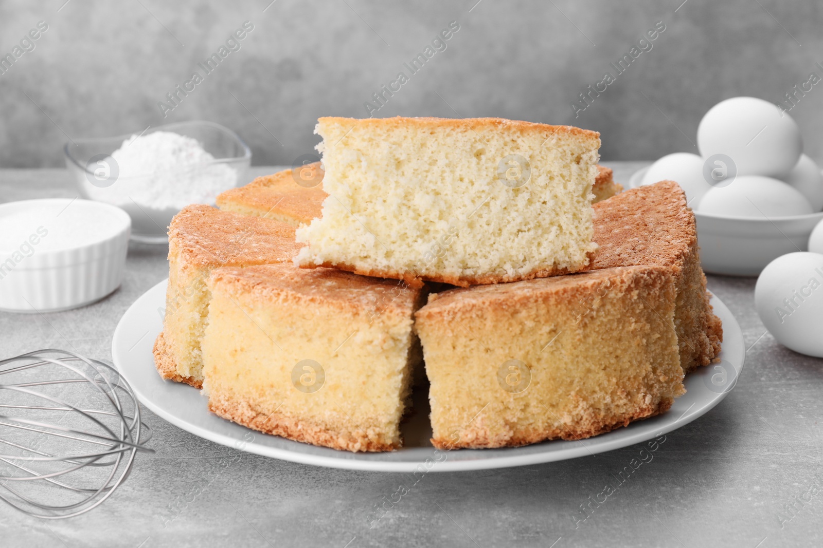 Photo of Pieces of tasty sponge cake on light grey table, closeup