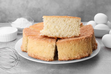 Pieces of tasty sponge cake on light grey table, closeup