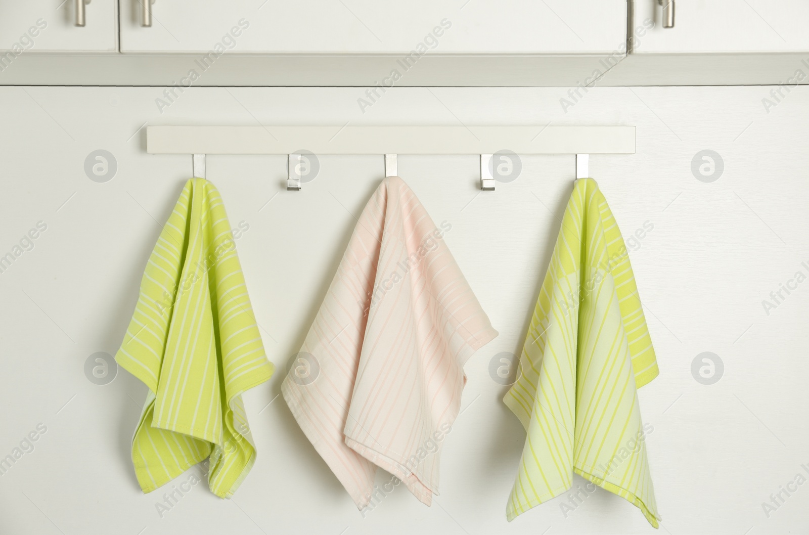 Photo of Different kitchen towels hanging on hook rack indoors