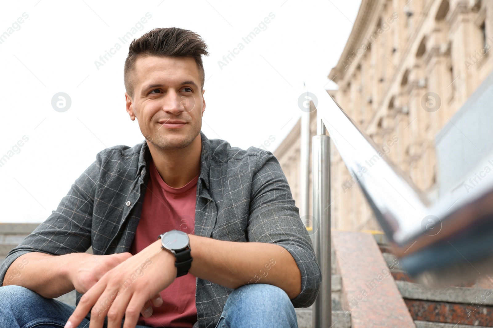 Photo of Portrait of handsome young man sitting on stairs outdoors