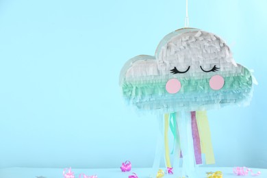 Photo of Cloud shaped pinata hanging on light blue background. Space for text