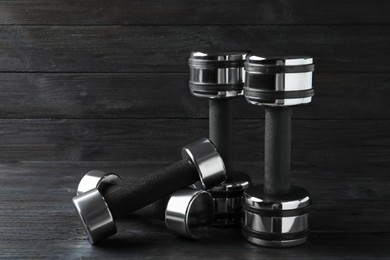 Photo of Set of metal dumbbells on black wooden table
