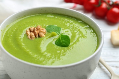 Photo of Bowl of broccoli cream soup with walnut on table, closeup