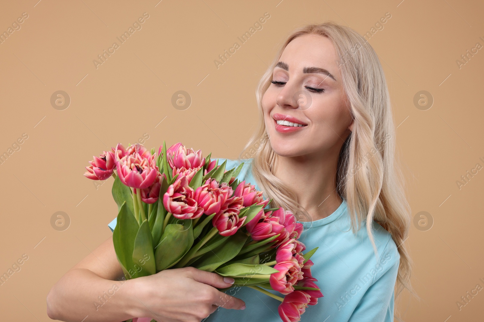 Photo of Happy young woman with beautiful bouquet on beige background