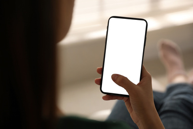 Image of Woman holding mobile phone with empty screen indoors, closeup