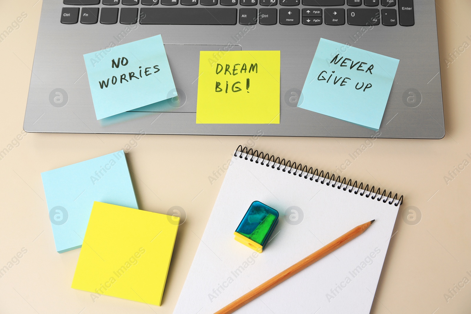 Photo of Paper notes with life-affirming phrases and laptop on white table, above view