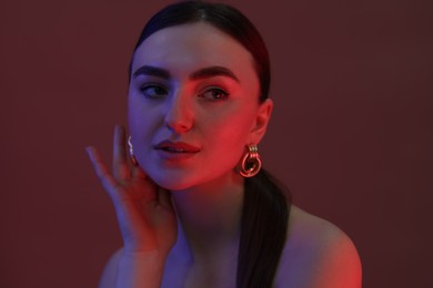 Portrait of beautiful young woman on color background in neon lights, closeup