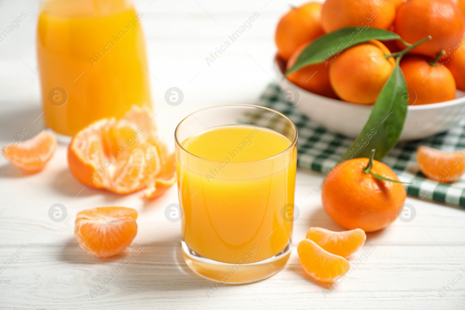 Photo of Glass of fresh tangerine juice and fruits on white wooden table